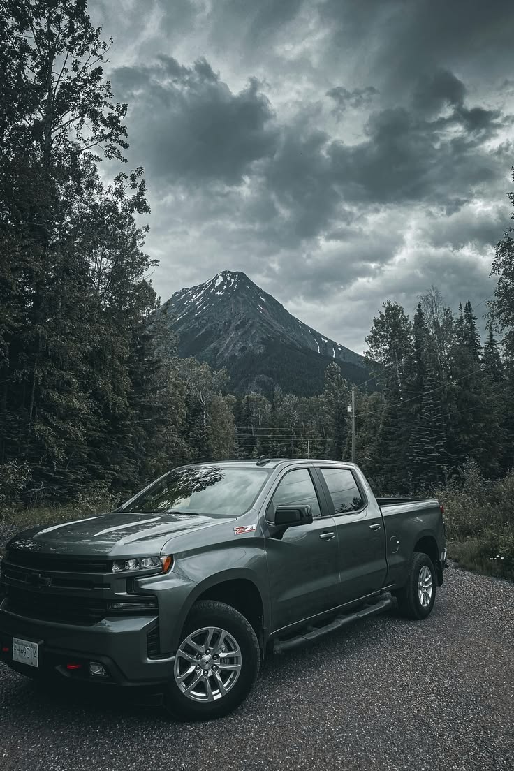 Grey Chevy Silverado truck on mountain road with stormy sky